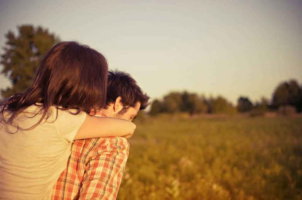 A picture of a woman hugging her partner from behind