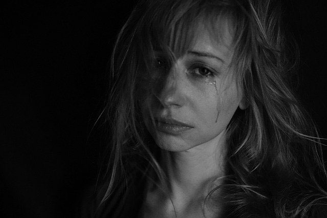 A black and white closeup photo of a woman crying